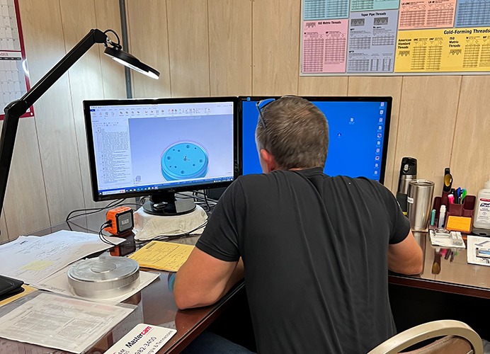 Avans programmer reviewing toolpaths on dual monitors using Mastercam software in a machining workspace.