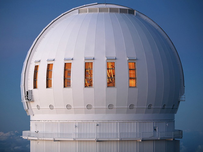 Canada France Hawaii Telescope (CFHT) dome at Maunakea, featuring illuminated windows, showcasing advanced astronomical research capabilities and precision engineering.