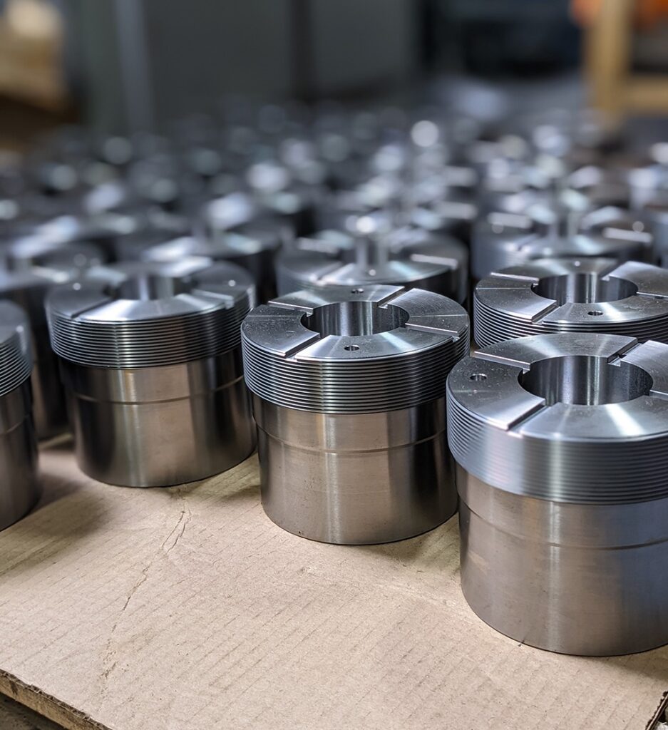 Metal cylindrical parts with staggered herringbone teeth, arranged for 5-axis milling process, showcasing Avers Machine and Gear's manufacturing capabilities.