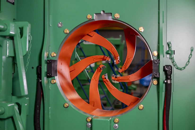 Multiaxis debarker knife assembly viewed through a circular opening, showcasing advanced manufacturing technology for the lumber industry.