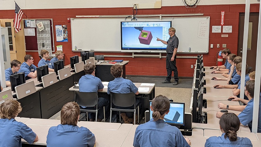 Instructor teaching Mastercam CNC programming to students in precision machining class, with a focus on toolpath creation and G-code on the screen.