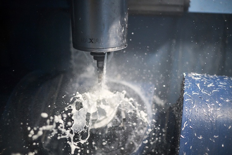 Milling machine in action, cutting a part with coolant spray, showcasing Dynamic Mill toolpaths for precision machining in medical automation.