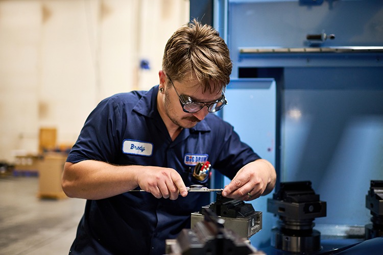 Technician adjusting precision machining equipment at Big Drum Precision Machining, emphasizing high-precision part production for automated medical lab cells.