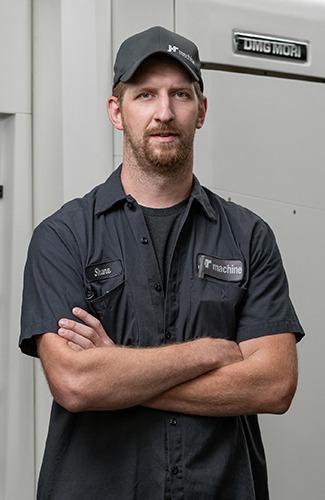 Shane Kunschke, VP of Manufacturing at JR Machine, posing confidently in a work uniform, showcasing expertise in precision machining for the aerospace industry.